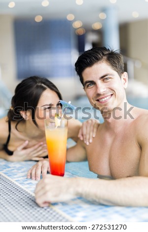 Portrait of a beautiful young couple smiling and drinking a cocktail in a pool
