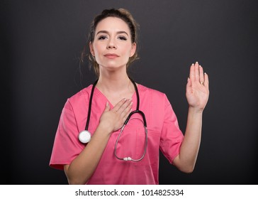 Portrait Of Beautiful Young Doctor Taking Oath On Black Background