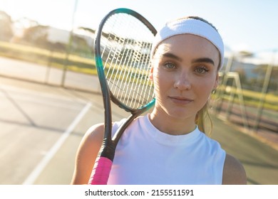 Portrait Of Beautiful Young Female Caucasian Tennis Player Wearing Headband Holding Racket Court. Unaltered, Sport, Competition And Tennis Game Concept.