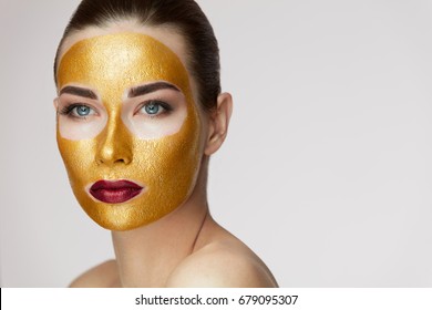 Portrait Of Beautiful Young Female With Cosmetic Gold Mask On Beauty Face.