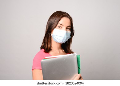 Portrait Of Beautiful Young Female Student Isolated On White Background Wearing A Covid 19 Surgical Mask Protection