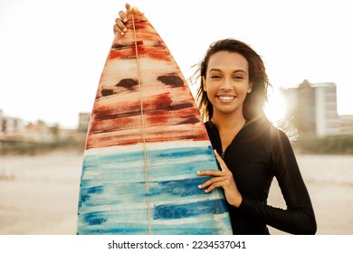 Portrait of a beautiful young female surfer posing with her surfboard at the beach - Powered by Shutterstock