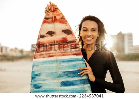 Portrait of a beautiful young female surfer posing with her surfboard at the beach