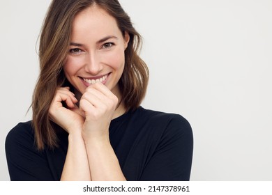 Portrait of beautiful young female or woman looking happy and confident in camera. Big smile on her face, looking beautiful standing isolated on white background. Concept: having a secret.