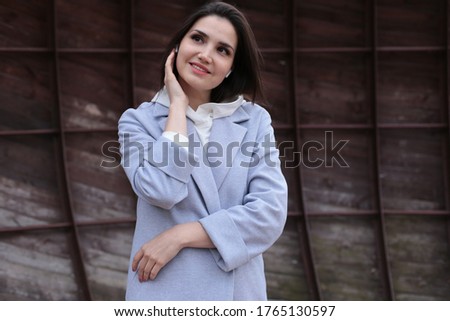Portrait of a beautiful young girl in a blue coat with wireless headphones