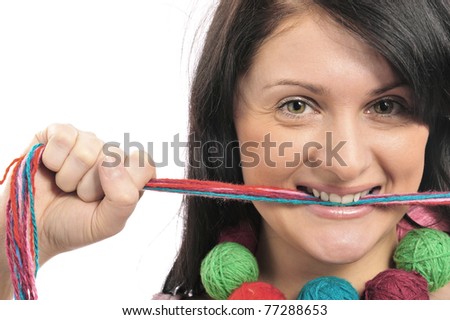 Portrait of a beautiful young girl with colored yarn in her mouth.  Isolated white background.