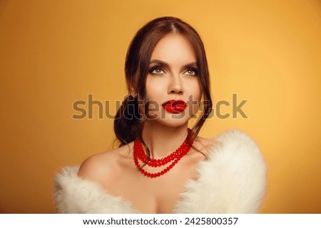 Portrait of beautiful young girl with red lips and bare shoulders in white furl coat on yellow studio background.  Alluring woman with hope looking up. skincare and wellness concept.