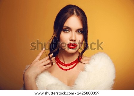 Portrait of beautiful young girl with red lips and bare shoulders in white furl coat on yellow studio background.  Alluring woman with perfect skin looking at camera. skincare and wellness concept.
