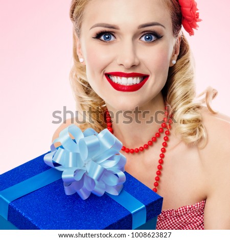 Portrait of beautiful young happy smiling woman in pin-up style clothing, over pink background. Caucasian blond model posing in retro fashion and vintage concept studio shoot.