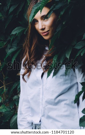 Portrait of beautiful young happy woman in a green wall of wild grapes