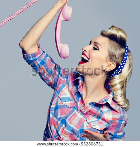 Portrait of beautiful young happy woman with phone, dressed in pin-up style. Caucasian blond model posing in retro fashion and vintage concept studio shoot. Square composition.