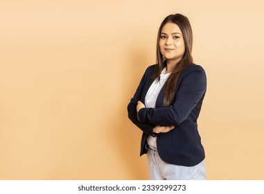 Portrait of beautiful young indian business woman wearing formal suit standing with her arms crossed isolated over beige background. Corporate concept. Copy space. - Powered by Shutterstock