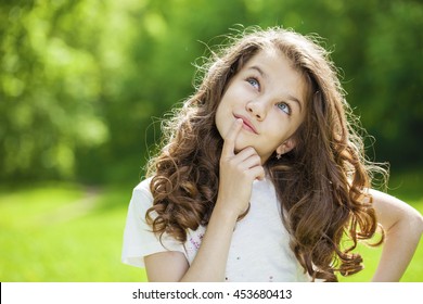 Portrait of a beautiful young little girl on the background of summer park