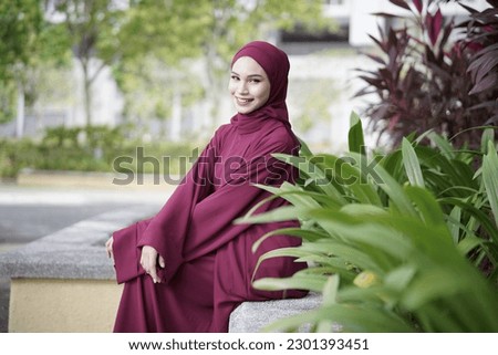 Portrait of beautiful young Muslim girl wearing Hijab and Jubah dress in outdoor scenes.Stylish Muslim female hijab fashion lifestyle portraiture concept.