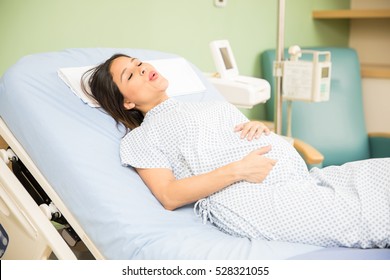 Portrait Of A Beautiful Young Pregnant Woman Trying To Breath To Soothe The Pain Of Her Labor Contractions In A Hospital