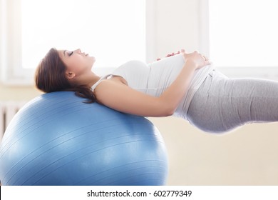 Porträt einer schönen jungen schwangeren Frau Übungen mit Fitball im Fitnessraum. Training und Fitness, Schwangerschaftskonzept.