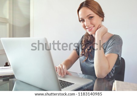 Portrait of beautiful young professional woman working from home desk with laptop computer, office interior. Smart female using technology, college student lifestyle.