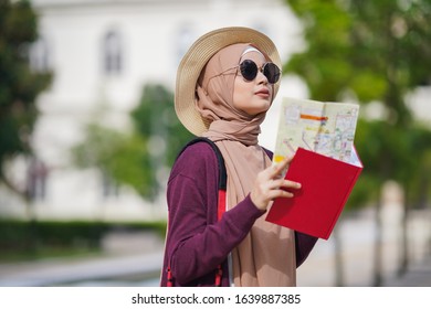 Portrait of beautiful young solo Muslim traveler exploring the city viewing the map - Shutterstock ID 1639887385