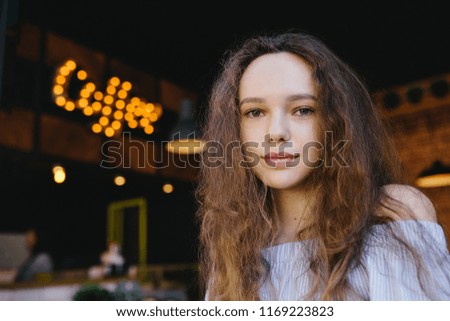 portrait beautiful young teenager girl with curly hair in cafe with signboard coffee