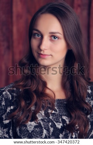 Portrait of a beautiful young woman against wooden wall. Beautiful smile on the face of the girl.