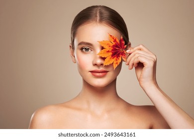 Portrait of beautiful young woman with autumn leafs. Healthy clean fresh skin natural make up beauty eyes