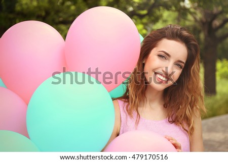 Portrait of beautiful young woman with balloons on blurred background
