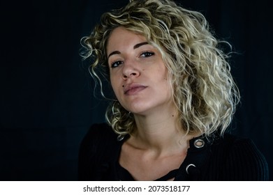 Portrait of a beautiful young woman with blond curly hair looking with her head tilted back