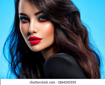 Portrait of beautiful young woman with bright blue makeup. Beautiful brunette with bright red lipstick on her lips. Pretty girl with long black hair. Closeup face of brunette woman.