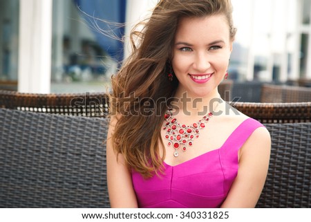 Portrait of a beautiful young woman in bright fashion dress in a summer restaurant