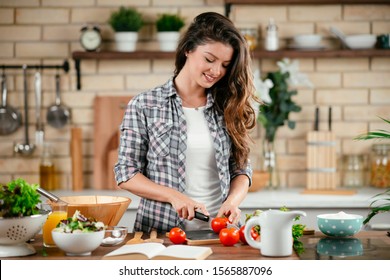 Portrait Of Beautiful Young Woman Cooking In The Kitchen. 
Young Woman Cooking. Healthy Food - Vegetable Salad.