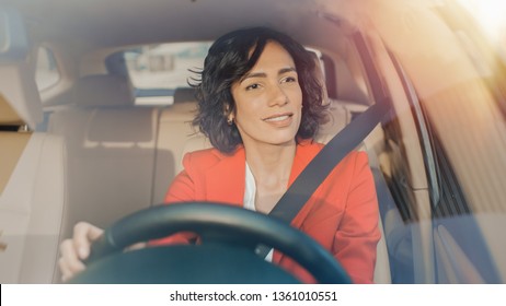 Portrait Of Beautiful Young Woman Driving Car Through Big Sunny City. Camera Shot Made From The Front Windshield.