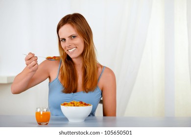 Portrait of a beautiful young woman eating cereals and strawberry for breakfast at home - Shutterstock ID 105650501