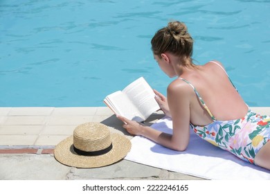 Portrait of beautiful young woman enyojing hot day reading a book next to the swimingpool. Relaxing summer vacation concept.	 - Powered by Shutterstock