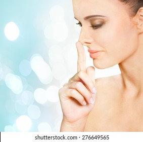 Portrait Of Beautiful Young Woman With Fingertip Touching Her Nose