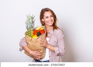 Portrait of beautiful young woman grocery shopping bag with vegetables at home. Young woman holding grocery shopping bag with vegetables - Powered by Shutterstock