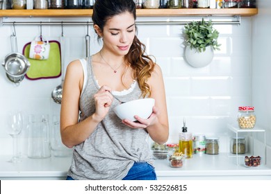 Portrait of beautiful young woman having breakfast in the kitchen. - Powered by Shutterstock