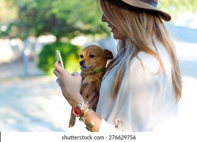 Portrait Of Beautiful Young Woman With Her Dog Using Mobile Phone.