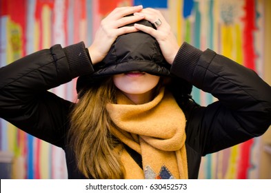 Portrait of beautiful young woman hiding face with hoodie.