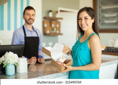 Portrait Of A Beautiful Young Woman Holding A Box Of Cupcakes She Just Bought In A Cake Shop And Smiling