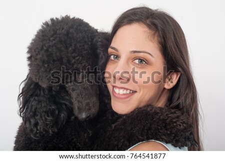 Portrait of a beautiful young woman hugging her beautiful dog. Big black poodle. Studio shoot