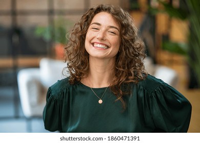 Portrait of beautiful young woman laughing at creative office. Happy businesswoman with curly hair excited with toothy smile. Enthusiastic cheerful girl looking at camera. - Shutterstock ID 1860471391