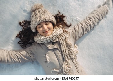 Portrait of a beautiful young woman laying down with closed eyes on a frozen snow lake playing games during a sunny winter vacation. Mixed race Asian Caucasian gorgeous girl resting during winter - Powered by Shutterstock