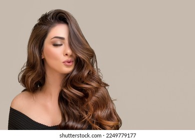 portrait of a beautiful young woman with long brown wavy hair. The face is closed by half of the voluminous hair. air kiss - Powered by Shutterstock