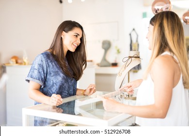 Portrait Of A Beautiful Young Woman Looking At Some Necklaces And Smiling To The Salesperson At The Store