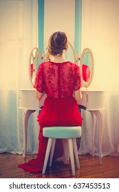 portrait of beautiful young woman  looking at herself in the wonderful mirror and sitting next to it