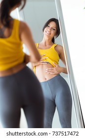 Portrait of beautiful young woman looking herself reflection in mirror at home.