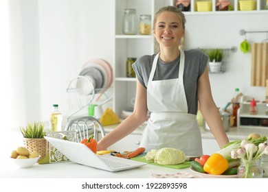 Portrait of beautiful young woman making salad at home