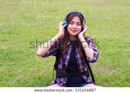 portrait of a beautiful, young woman with music sitting on grass.