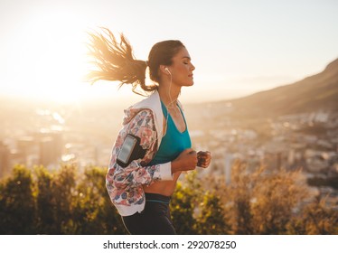 Portrait of beautiful young woman out for a run on a hot sunny day. Caucasian female model jogging outdoors. - Powered by Shutterstock