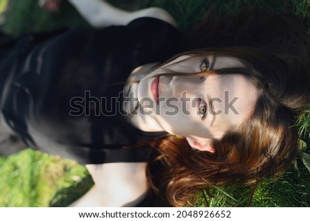 Frau in einem Blumenfeld bedeckt sich vor Sonnenlicht.